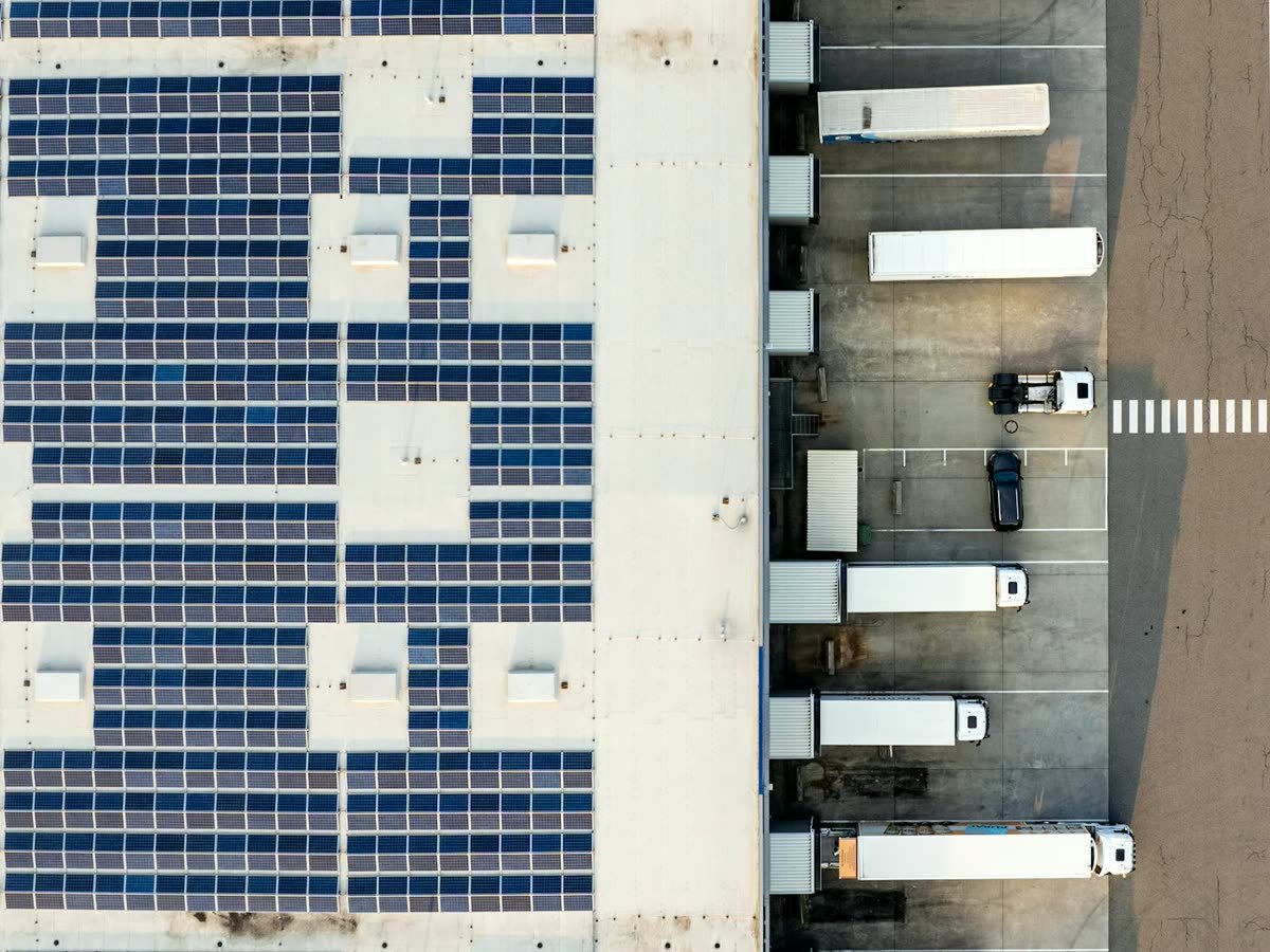 Cubierta de una bodega industrial llena de paneles solares, con los camiones en los muelles de carga