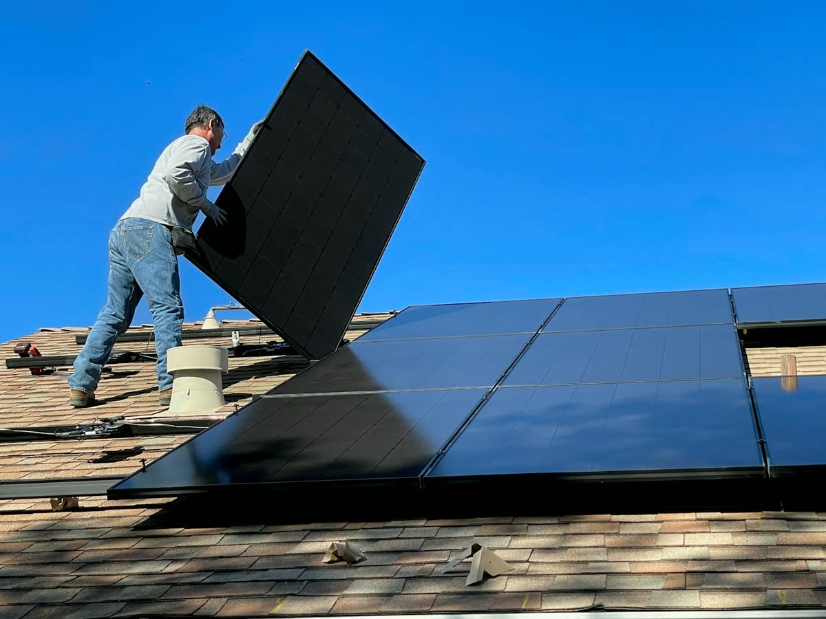 Instalador colocando un panel solar en el tejado de una vivienda