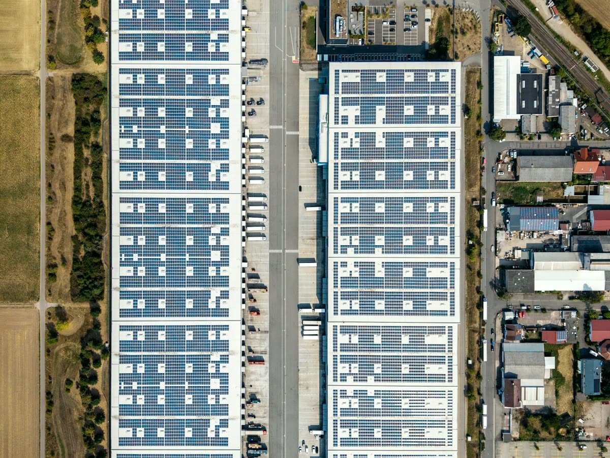 Vista aérea de dos bodegas industriales con las cubiertas llenas de paneles solares